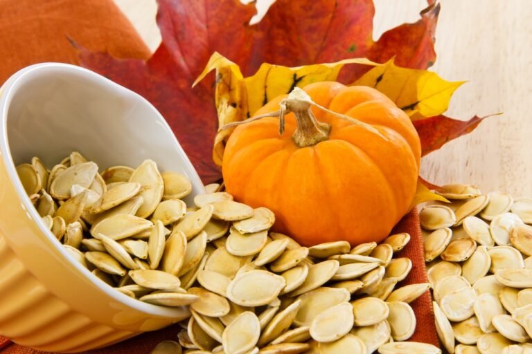 Toasted pumpkin seeds spilling from a yellow bowl